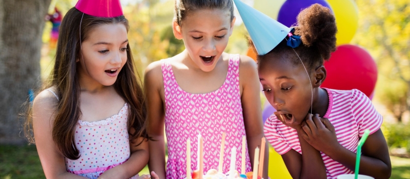 Portrait of cute girls preparing to blow on candle during a birthday party